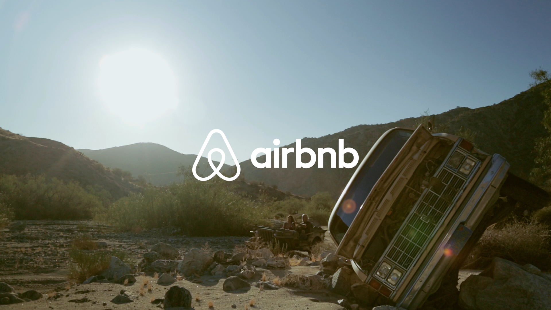 Airbnb logo on top of a picture of old truck in the desert