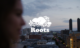 Roots logo on top of image of a woman on rooftop in city